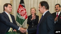 Afghan Trade Minister Anwar Ul Haq Ahadi (left) shakes hands with Pakistani Trade Minister Makdoom Amin Fahim as U.S. Secretary of State Hillary Clinton and Pakistani Prime Minister Syed Yousaf Raza Gillani look on in Islamabad on July 18.