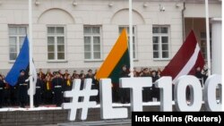 Flags of Estonia, Lithuania, and Latvia during a flag-raising ceremony next to the Presidential Palace during the country's centenary celebration in Vilnius on February 16.