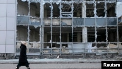 Женщина проходит возле разрушенного здания в Донецке. Февраль 2015 года