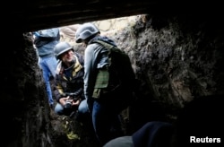 Jurnaliști coboară într-un adăpost în Delbațevo, în timpul unui bombardament.