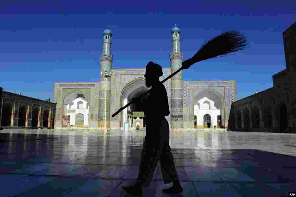 A man carries a broom as he walks past the main mosque in Herat, Afghanistan, during Ramadan. (AFP/Aref Karimi)