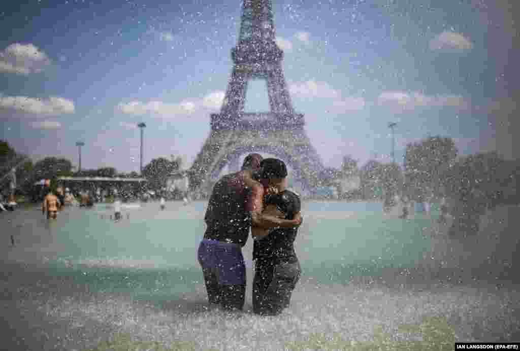 A couple cool down in the fountains of Trocadero, across from the Eiffel Tower, during a heatwave in Paris, France. (epa-EFE/Ian Langsdon)