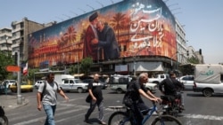 People pass a billboard depicting Iran's late Supreme Leader Ayatollah Ali Khamenei embracing late senior Iranian military commander General Qassem Soleimani, in Tehran on June 28. 