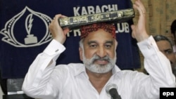 Zulfiqar Mirza, a senior minister in the southern Sindh Province, holds the Koran aloft as he announces his resignation from the government