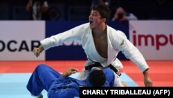 Georgia's Luka Maisuradze (in white) celebrates winning the bronze medal in his fight against Iran's Saeid Mollaei in the men's under 81kg category during the 2019 Judo World Championships.