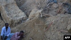 Pakistan -- A Pakistani mourner talks on a mobile phone at the site of a landslide in Karachi, October 13, 2015