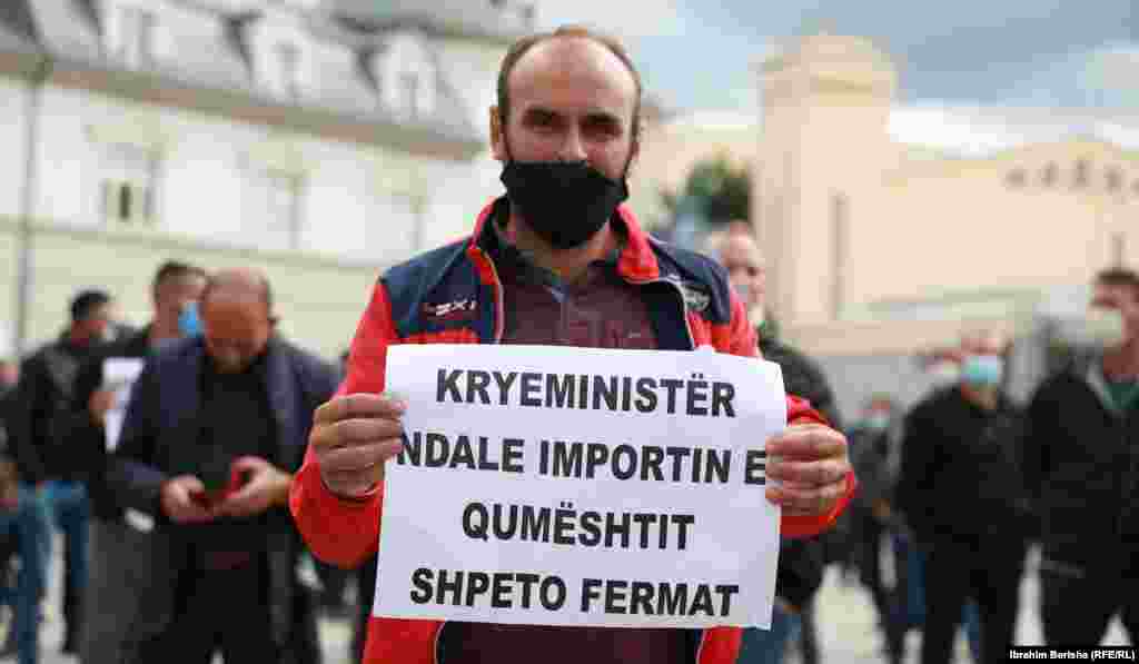 Një protestues mban pankartën me mbishkrimin &quot;Kryeministër, ndale importin e qumështit, shpëto fermerët&quot;.