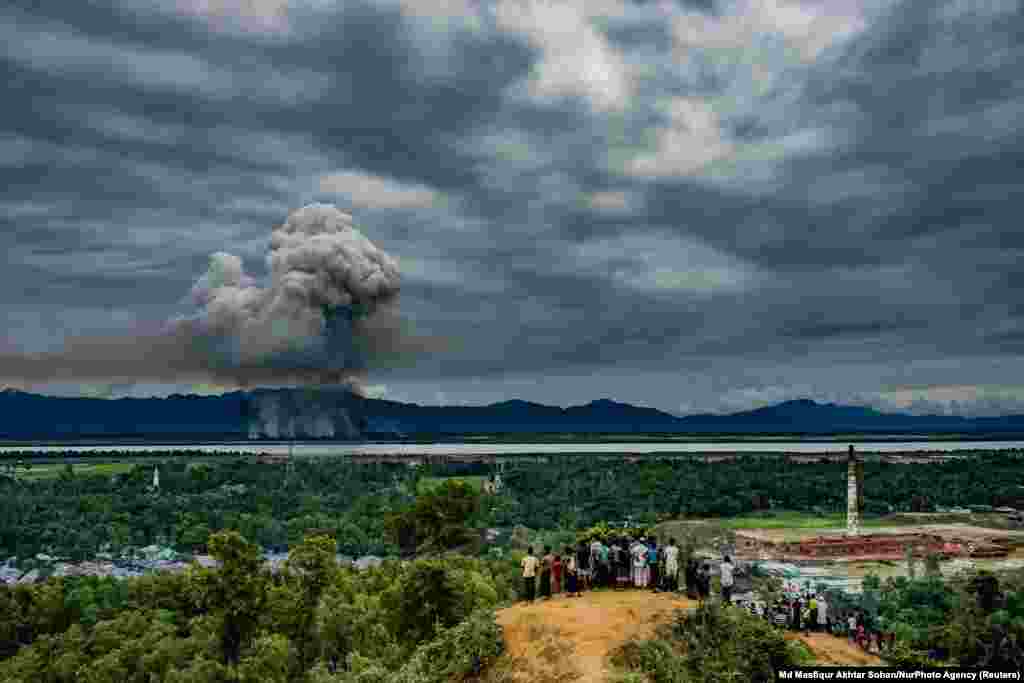 A group of Rohingya refugees in Cox's Bazaar, Bangladesh, watch as houses burn across the border in Myanmar. General News -- Third Prize, Singles (Md Masfiqur Akhtar Sohan, NurPhoto Agency)