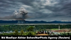 Refugiați Rohingya urmărind cum ard case peste graniță, în Myanmar