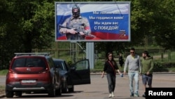 People walk near a banner in support of the Russian Army in Vyborg, Russia.