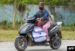 O femeie conduce motocicleta transportând saci de cărbuni pe o stradă din Havana, pe 6 februarie 2026.