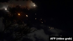 Rachete iraniene deasupra Israelului. Captură după un videoclip AFP. Imagini transmise de BBC și CNN au arătat că proiectile sau resturi de rachete interceptate au explodat la sol.