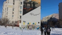 Çagalar ýaşaýyş jaýyň diwarynda söweş meýdanyndaky harbylary şekillendirýän suratyň öňünden geçýärler. Kiýew, 2026-njy ýylyň fewraly.