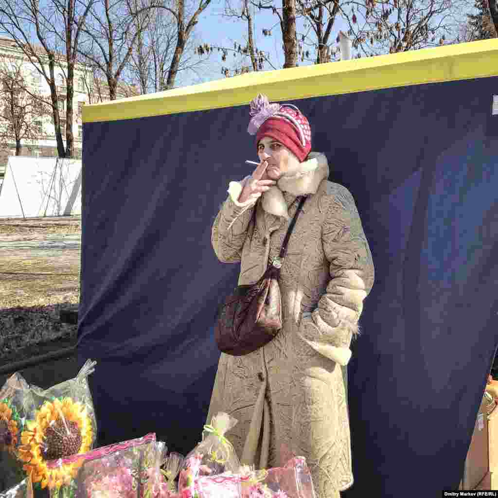 A woman sneaks a puff of her cigarette while watching over her souvenir stall.&nbsp;