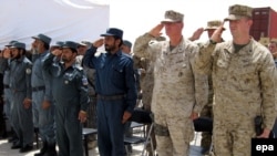 Afghan police and U.S. Marines salute during a ceremony marking conclusion of the Afghans' training.