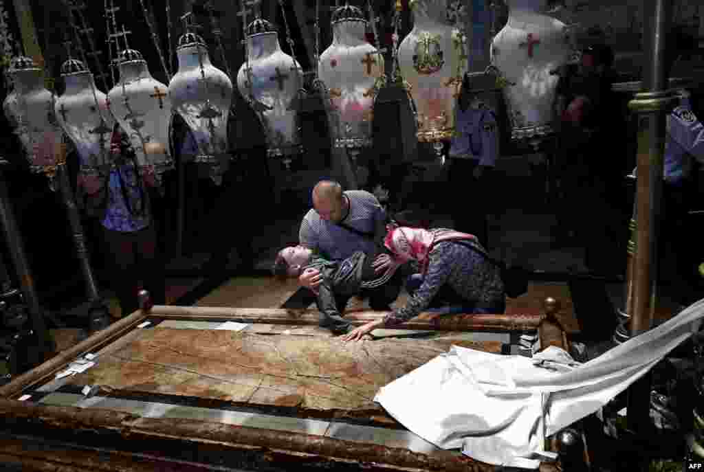 Christian Orthodox pilgrims pray with their handicapped son inside the Church of the Holy Sepulchre in Jerusalem’s Old City during Good Friday celebrations on April 29. (AFP/Thomas Coex)