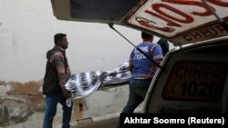 Rescue workers move one of two bodies of a couple who was killed by family members outside the hospital morgue in Karachi on November 27.