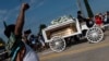 A man raises his fist as mourners watch the casket of George Floyd carried by a white horse-drawn carriage to his final resting place at the Houston Memorial Gardens cemetery in Pearland, Texas on June 9, 2020.