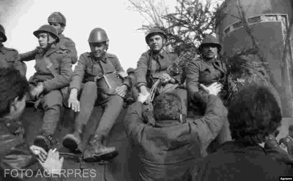 București, 22 decembrie 1989. Un manifestant oferă flori soldaților de pe tanc. Gestul a fost frecvent în zilele Revoluției.&nbsp;