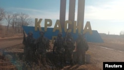 An image, released on February 12 by Yevgeny Prigozhin's press service, shows what are said to be Wagner fighters posing for a picture at the entrance sign to the village of Krasna Hora near the embattled city of Bakhmut.