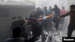 Residents and Civil Defense members carry the body of an elderly woman on a stretcher amid rubble of damaged buildings after an air strike on the rebel-held Al-Saliheen district in Aleppo on March 11.