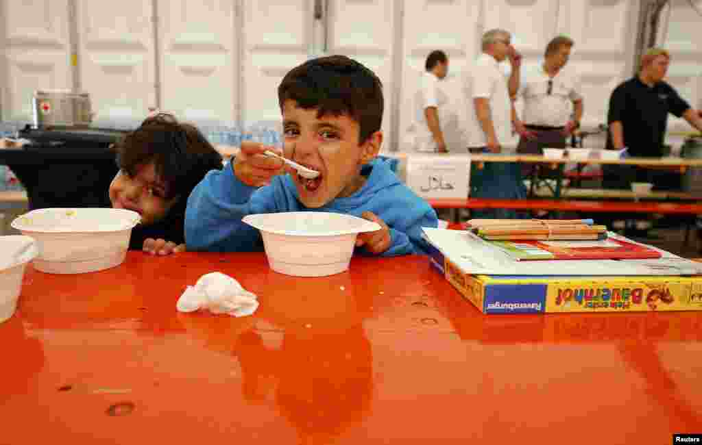 A migrant boy eats as he sits inside a catering tent near an improvised temporary shelter in a sports hall in Hanau, Germany. (Reuters/Kai Pfaffenbach)