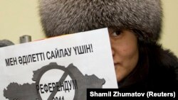 Алматыдағы ЕҚЫҰ кеңсесі алдында плакат ұстап тұрған белсенді. Қаңтар айы, 2011 жыл.