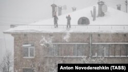 Men clear snow off a roof in Moscow on February 4.