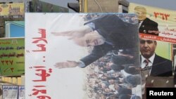 Residents remove a campaign billboard from a street in Baghdad on March 8, one day after the voting.