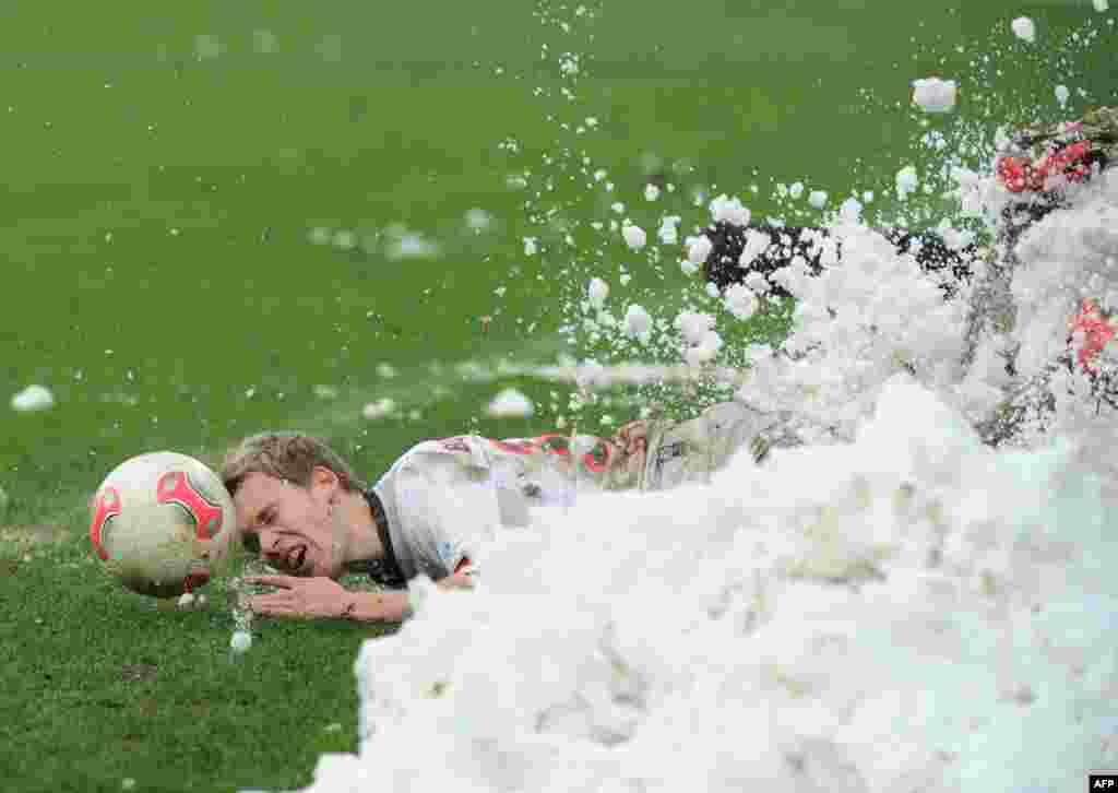St. Pauli's Christopher Buchtmann slides into a heap of snow during a Bundesliga match between FC St. Pauli and Erzgebirge Aue at Millerntor-Stadion in Hamburg, Germany. (AFP/Angelika Warmuth)
