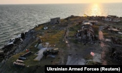 Українські військовослужбовці йдуть поруч зі зруйнованими будовами на острові Зміїному в Чорному морі (Одеська область). Фото опубліковане прес-службою ЗСУ 7 липня 2022 року