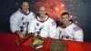 Echipajul inițial Apollo 13, James A. Lovell - Thomas K. Mattingly - Fred W. Haise, cu însemnele Apollo 13 și un model de sextant și un astrolab, instrumente străvechi de navigație. Mattingly a fost expus rujeolei și a fost înlocuit cu John L. "Jack" Swigert Jr.