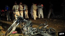 Officers stand beside the wreckage of a motorbike after a bomb exploded in Karachi earlier this month, part of a wave of bombings that has struck Pakistani cities. 
