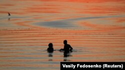 Пара купаецца на захадзе сонца ў возеры пад Менскам