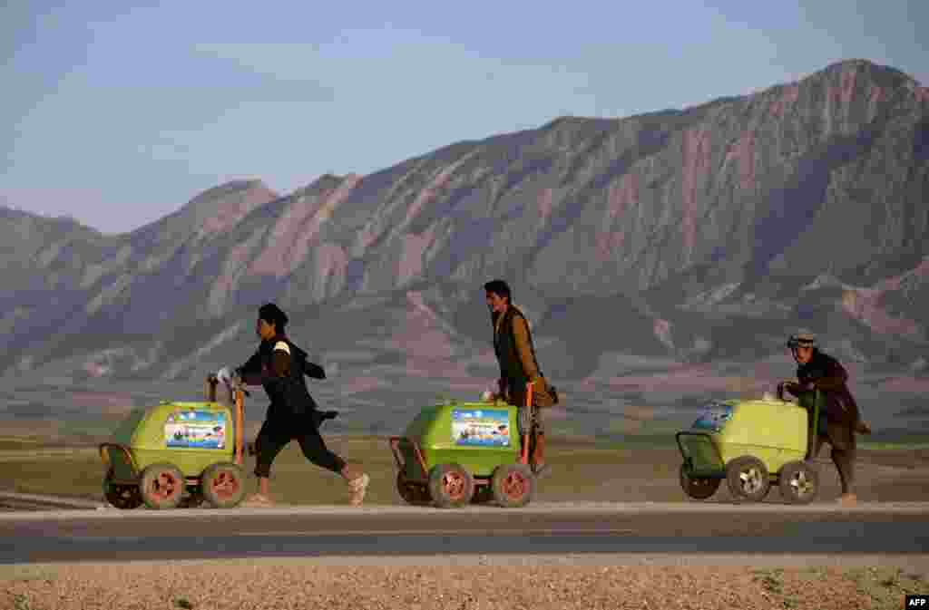 Young Afghan vendors push their ice-cream carts along a road on the outskirts of Mazari-e Sharif on March 23. (AFP/Farshad Usyan)