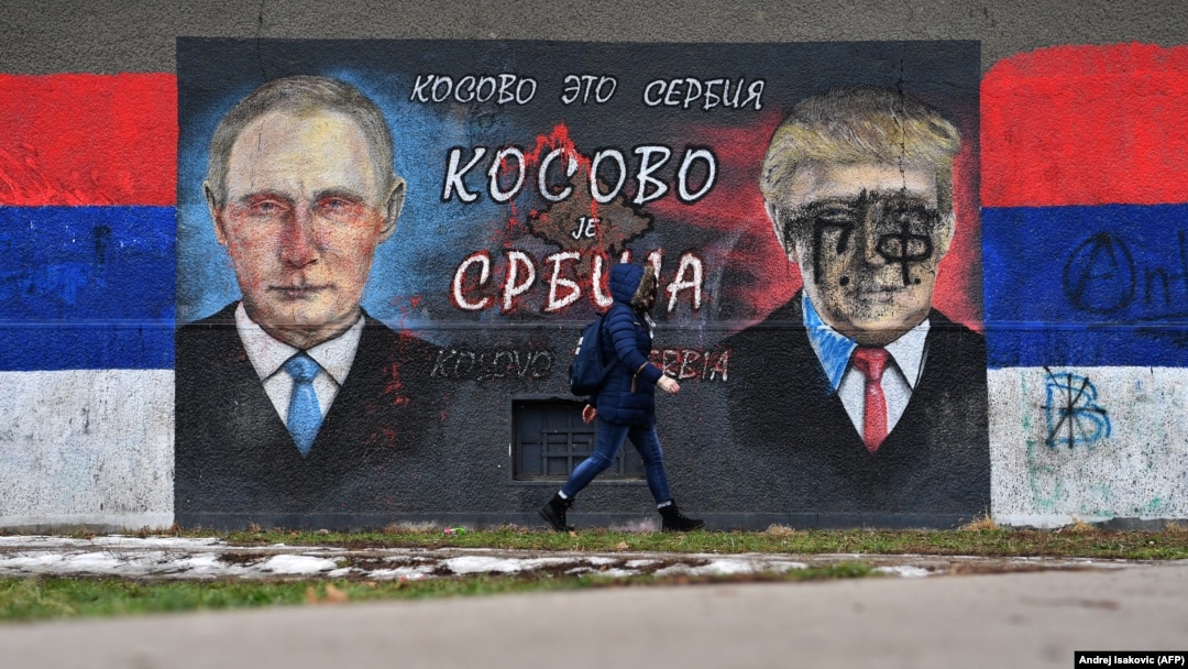A woman walks past a mural depicting Russian President Vladimir Putin and U.S. President Donald Trump in Belgrade.