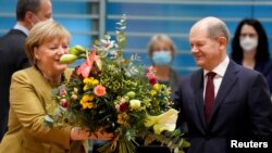 Cancelara germană în exercițiu Angela Merkel primește un buchet de flori de la succesorul ei, social-democratul Olaf Scholz, în acest moment ministru de Finanțe. Berlin, 24 noiembrie 2021.