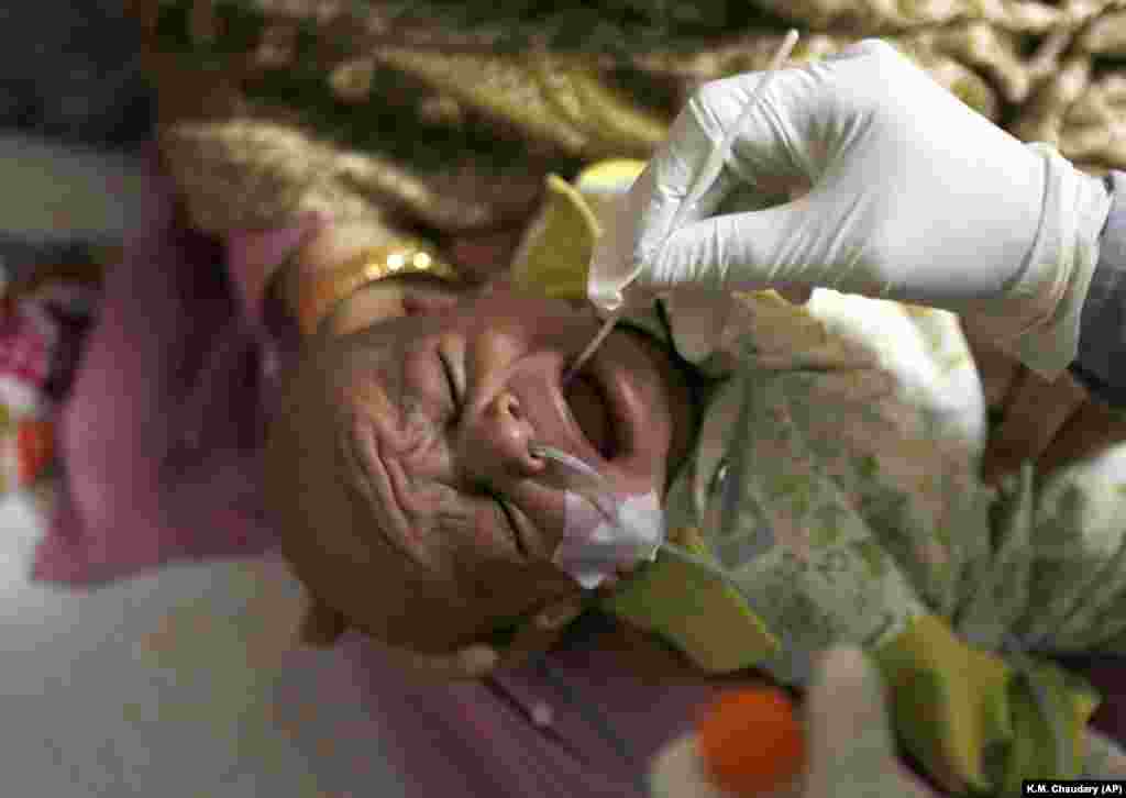 Медработник берет мазок из горла у ребенка в центре тестирования на COVID-19 в больнице в Лахоре, Пакистан