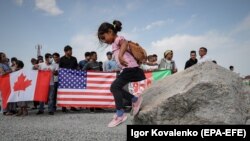 KYRGYZSTAN -- A girl play on a rock as Afghan refugees protest in front of the U.S. embassy in Bishkek, August 19, 2021