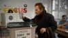 A woman casts her ballot as part of the general elections at a polling station in Pristina on February 9, 2025.