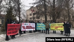 Участники митинга в Шымкента с плакатами на казахском и русском языках: «Президент, чем помогать другой стране, стань благодетелем для собственной!», «В правовом государстве широко процветают финансовые пирамиды» 