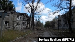 Străzile pustii din Bilozerske, cu blocuri distruse de atacurile rusești. Pe plăcuța unuia dintre imobile scrie: str. Moskovska