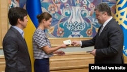 Ukrainian President Petro Poroshenko (right) gives Ukrainian citizenship to Russian public figure Maria Gaidar (center) in Kyiv on August 4.
