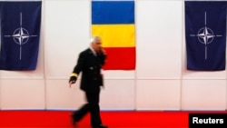 Военнослужащий проходит мимо флагов Румынии и НАТО на одном из мероприятий в Бухаресте (фото архивное)