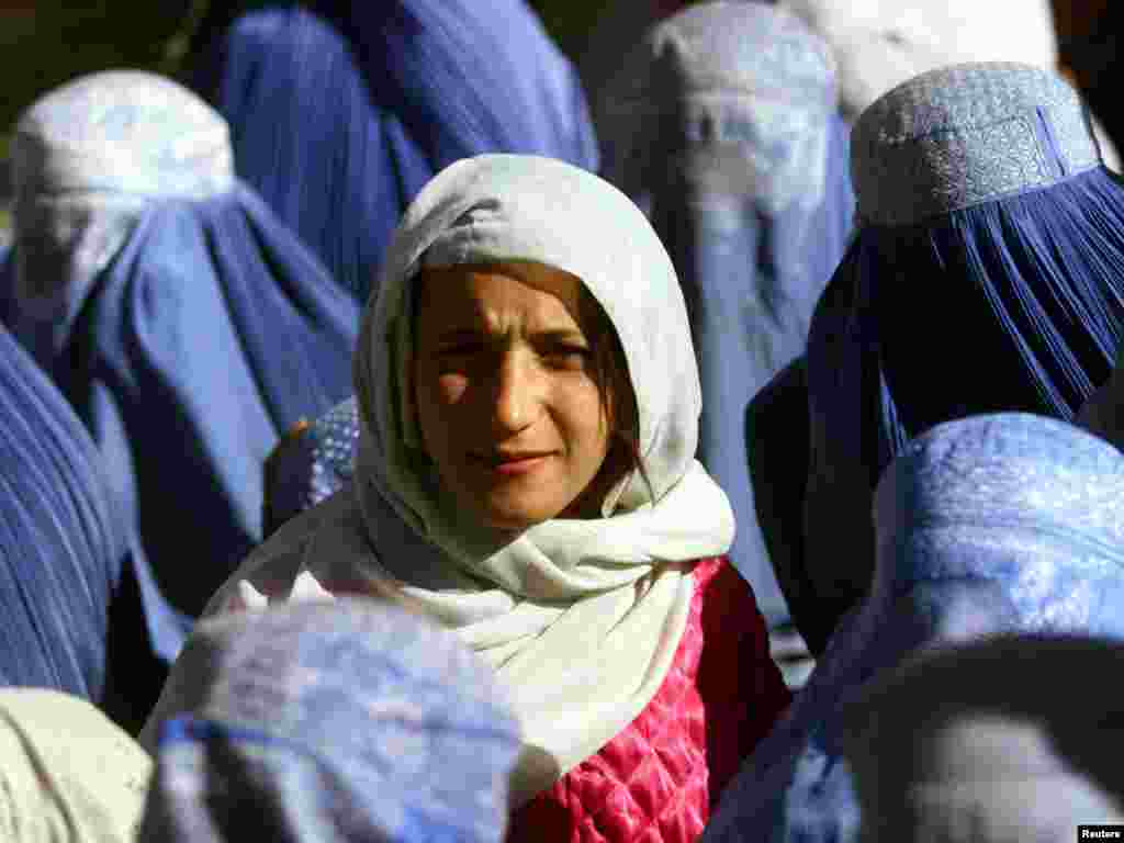 A young Afghan woman shows her face in public for the first time after 5 years of Taliban Sharia law as she waits at a food distribution centre in central Kabul November 14, 2001. Under its strict interpretation of Islam, the Taliban ordered all women hidden behind head-to-toe burqas. REUTERS/Yannis Behrakis
