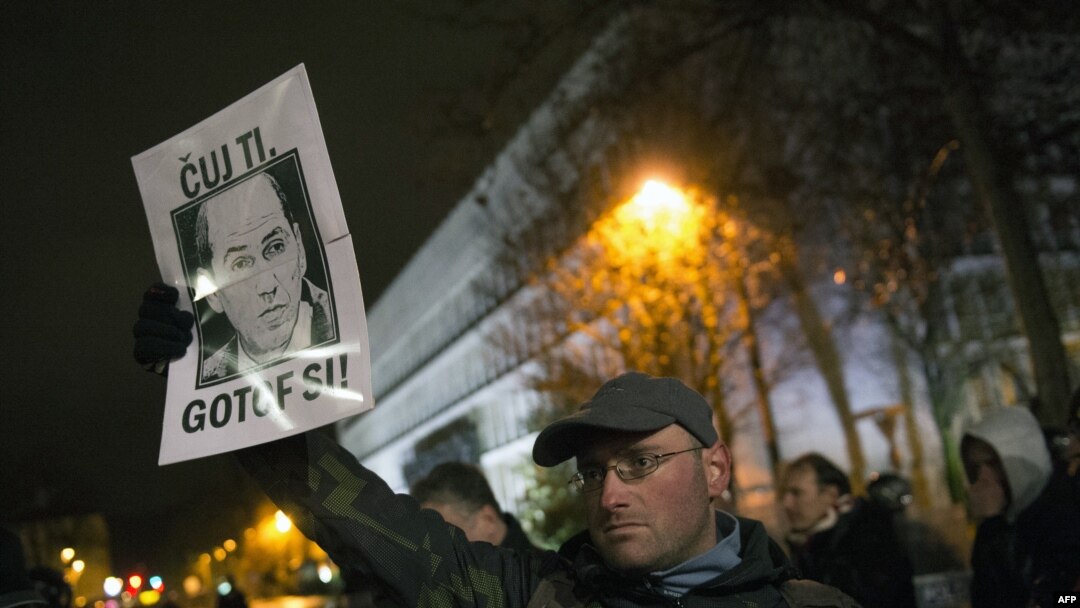 A protester shows a poster with Prime Minister Janez Jansa's portrait saying "He is done" in Slovenian during protests against the government in Ljubljana on November 30.