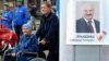 Belarus -- People walk past a poster bearing the image of Belarusian President Alyaksandr Lukashenka as his supporters collect signatures to register him as a candidate for the October 11 presidential elections, in Minsk, September 19, 2015