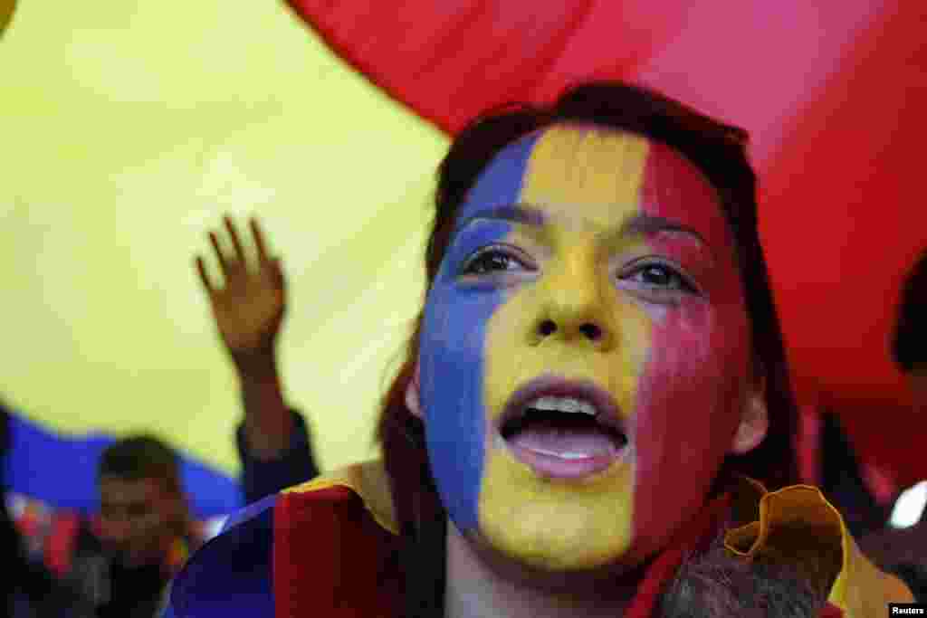 A woman with her face painted in the Romanian national colors shouts slogans during a march by Romanians and Moldovans through downtown Bucharest to demand the unification of Moldova and Romania. (Reuters/Bogdan Cristel)