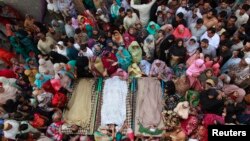 Relatives gather beside the bodies of victims who were killed in yesterday's suicide bomb attack on the Wagah border, before funeral prayers in Lahore on November 3, 2014.