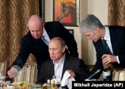 Российский бизнесмен, «повар Путина» Евгений Пригожин (слева) в своем ресторане подает блюдо Владимиру Путину, 11 ноября 2011 года